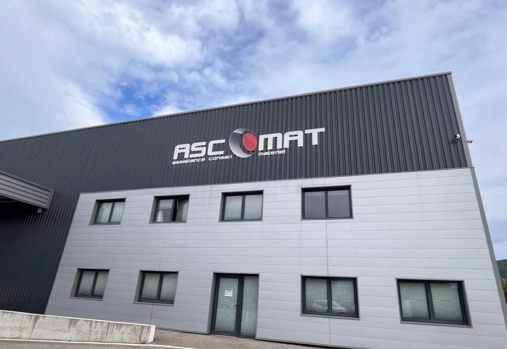 Enseigne de site industriel grand format en lettres découpées blanches et rouges sur bardage métallique pour Ascomat.